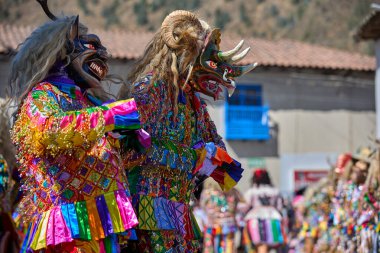 Şeytani maskeler ve akrobatik yeteneklerle, Saqras Paucartambo 'da dans ediyor, neşeli, alaycı ruhlar koruyor ve kışkırtıyor, enerji ve gerilim ekliyor. Bakire del Carmen