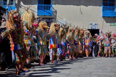 Şeytani maskeler ve akrobatik yeteneklerle, Saqras Paucartambo 'da dans ediyor, neşeli, alaycı ruhlar koruyor ve kışkırtıyor, enerji ve gerilim ekliyor. Bakire del Carmen