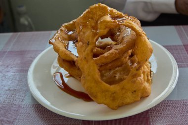 Altın, çıtır çıtır ve tatlı chancaca şurubuyla sulandırılmış bu Arequipa tarzı picarone 'lar mükemmel bir şekilde kızartılmış ve Peru usulü bir ikram olarak sunulan balkabağı ve tatlı patates hamurunun lezzetli bir karışımıdır..