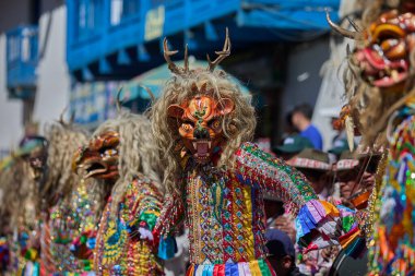 Şeytani maskeler ve akrobatik yeteneklerle, Saqras Paucartambo 'da dans ediyor, neşeli, alaycı ruhlar koruyor ve kışkırtıyor, enerji ve gerilim ekliyor. Bakire del Carmen