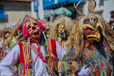 Şeytani maskeler ve akrobatik yeteneklerle, Saqras Paucartambo 'da dans ediyor, neşeli, alaycı ruhlar koruyor ve kışkırtıyor, enerji ve gerilim ekliyor. Bakire del Carmen