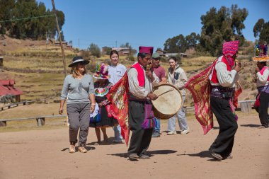 Taquille Adası, Puno, Peru 'da düzenlenen geleneksel bir kutlamada yerel dansçılara katılan bir turist için neşeli bir an.