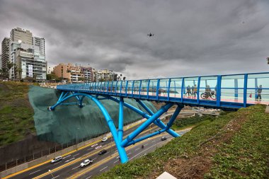 Miraflores 'deki yeni La Paz köprüsü kenti modern tasarım, cam zemin ve bisikletçileri ve yayaları Limas kentsel manzarasının tadını çıkarmaya davet eden renkli yollarla birbirine bağlıyor..