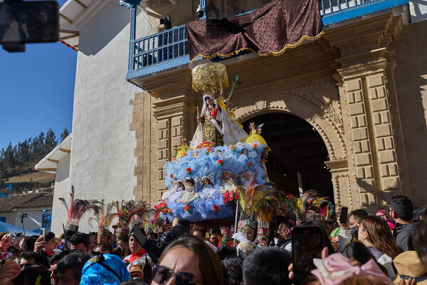 The solemn procession of La Virgen del Carmen emerges from the church in Paucartambo, surrounded by faithful devotees, music, and centuries-old tradition