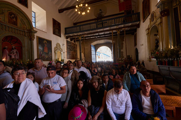 The solemn procession of La Virgen del Carmen emerges from the church in Paucartambo, surrounded by faithful devotees, music, and centuries-old tradition