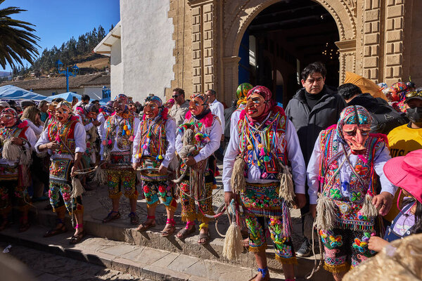 The solemn procession of La Virgen del Carmen emerges from the church in Paucartambo, surrounded by faithful devotees, music, and centuries-old tradition