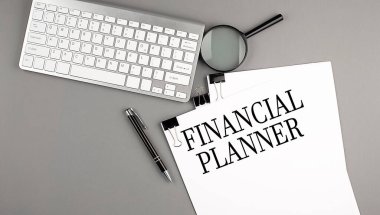 Gri arkaplan üzerinde klavye olan bir kağıt üzerinde FINANCIAL PLANNER metni