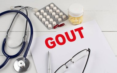 Steteskoplu ve haplı bir kağıtta Gout kelimesi