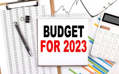 Çizelgesi, hesap makinesi ve kalemi olan bir defter üzerinde 2023 metin için bütçe