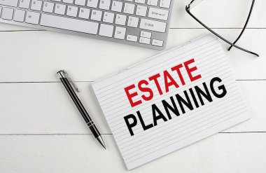 Not defterinde klavye, beyaz tahta zemin üzerinde kalem gözlüğü olan ESTATE Planlama metni