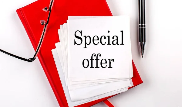 SPECIAL OFFER text on a sticker on red notebook with pen and glasses