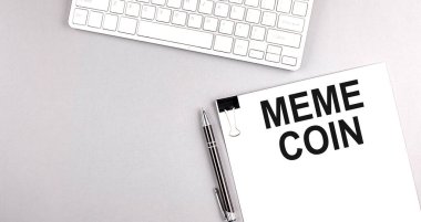 Gri arkaplan üzerinde klavye olan bir kağıt üzerinde MEME COIN metni