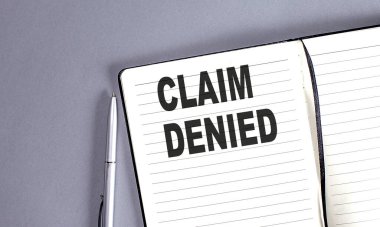 CLAIM DENIED kelime kalem ile defter üzerinde
