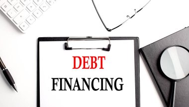 Ofis araçları ile bir kağıt pano üzerine yazılmış DEBT FINANCING metin