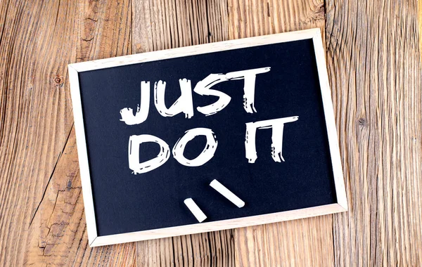 JUST DO IT text on a chalkboard on the wooden background