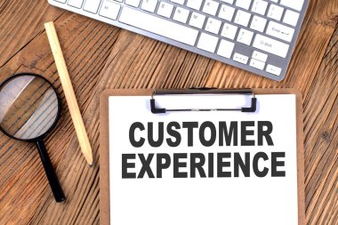 Tahta üzerinde büyüteç ve klavye olan kağıt pano üzerindeki CUSTOMER ExperIENCE metni