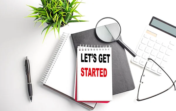 stock image Text LET'S GET STARTED on a notebook with office tools on white background