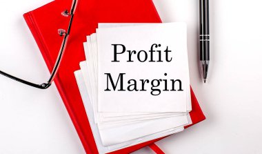 PROFIT MARGIN metin kırmızı defter üzerinde bir çıkartma kalem ve gözlük ile