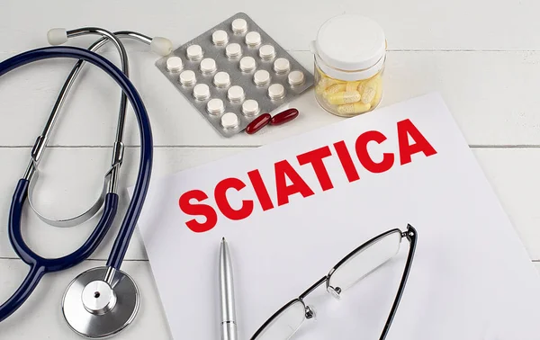 stock image SCIATICA word on a paper with stethoscope and pills