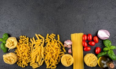 Siyah arka planda fotokopi alanı olan farklı ham makarna. İtalyan mutfak malzemelerinin üst görünümü.