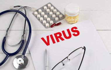 Steteskoplu ve haplı bir kağıtta VIRUS kelimesi