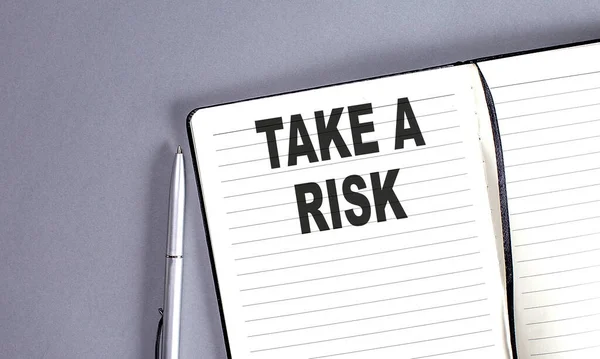 stock image TAKE THE RISK word on notebook with pen