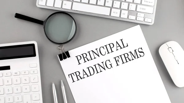 PRINCIPAL TRADING FIRMS written on paper with office tools and keyboard on grey background
