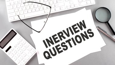 INTERVIEW QUESTIONS text on paper with keyboard, calculator on a grey background clipart