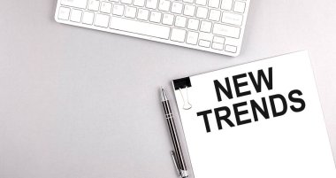 Gri arkaplan üzerinde klavye olan bir kağıt üzerinde yeni TRENDS metni