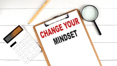 Beyaz ahşap arka planda hesap makinesi, büyüteç ve kalemle, panodaki zihin ayarlarınızı değiştirin