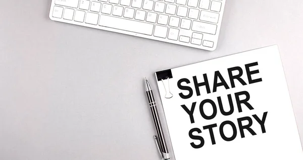 stock image SHARE YOUR STORY text on a paper with keyboard on grey background