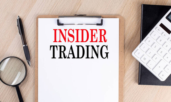 INSIDER TRADING text on clipboard on wooden background