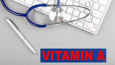 VITAMIN Gri arkaplanda bir klavyede steteskop ile bir kelime