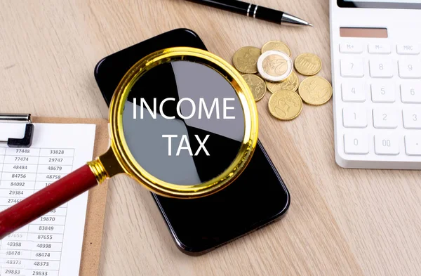 スマートフォン コインで拡大鏡の所得税テキスト — ストック写真