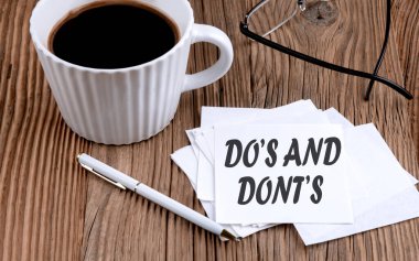 Do 's and Dont' un yapışkan üzerine yazdığı metin. Kahve ve kalem ile ahşap arka planda.