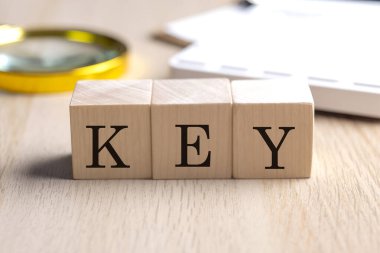Büyüteç ve hesap makineli ahşap küplerde anahtar, finansal konsept arka planı