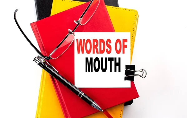 WORDS OF MOUTH text written on sticky on colorful notebooks