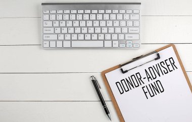 Beyaz ahşap arka planda DONOR ADVIDER ile klavye, pano ve kalem ile ev ofis çalışma alanı, iş