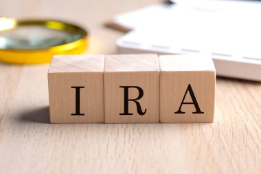 IRA, büyüteç ve hesap makinesiyle tahta küplerin üzerinde, finansal konsept arka planı