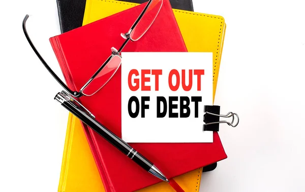GET OUT OF DEBT text written on sticky on colorful notebooks