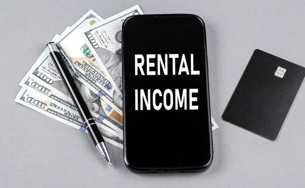 Akıllı telefondan dolar ve kalemle kredi kartı ve RENTAL gelir mesajı. İş konsepti