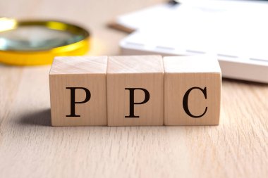 Büyüteç ve hesap makineli ahşap küplerde PPC, finansal konsept arka planı
