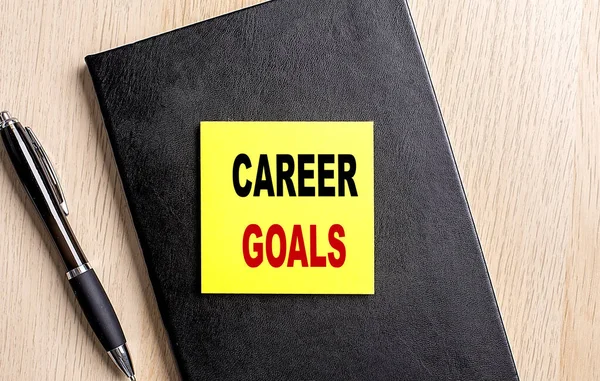 CAREER GOALS text on sticky on black notebook with pen