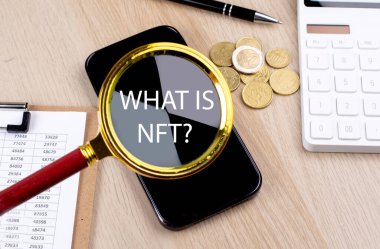 WHAT IS NFT text on magnifier with smartphone, calculator and coins