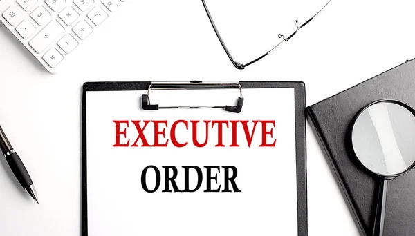 EXECUTIVE ORDER text written on a paper clipboard with office tools