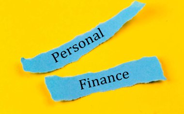 PERSONAL FINANCE text on blue pieces of paper on yellow background, business concept