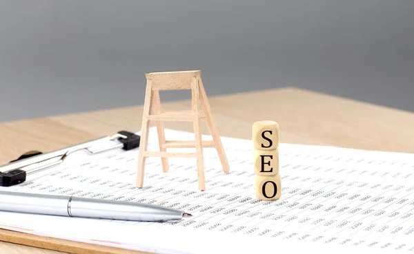 stock image wooden cubes with the word SEO stand on financial background, business concept.
