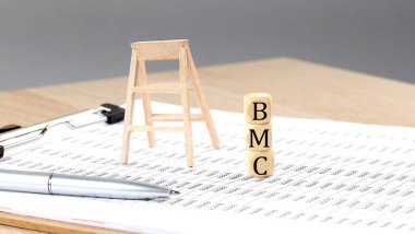 wooden cubes with the word BMC stand on financial background, business concept.