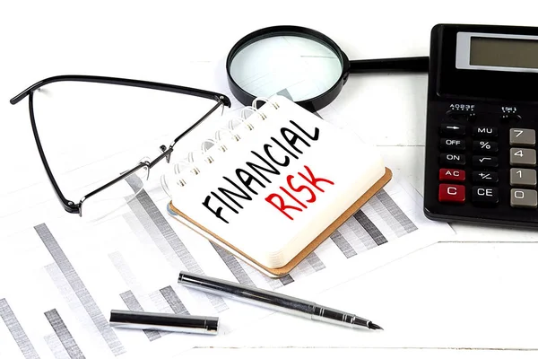 FINANCIAL RISK text on a notebook with calculator on diagram background