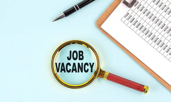 JOB VACANCY text on a magnifier with clipboard on blue background